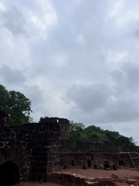 Laterite walls of Vijaydurg Fort under monsoon clouds